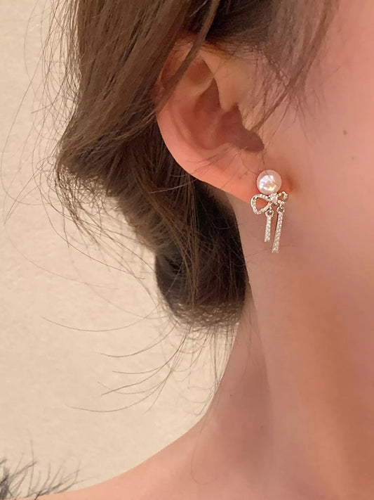 The Éloïse Pearl-Bow Earrings — sterling silver bow drop earrings with pearl
